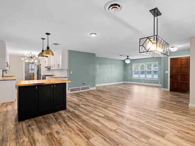 kitchen with stainless steel fridge, light wood-type flooring, pendant lighting, white cabinets, and butcher block countertops