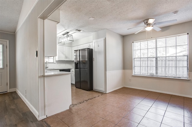 kitchen with white cabinets, a textured ceiling, black fridge, and ceiling fan