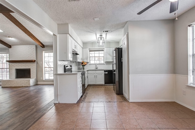 kitchen with light wood-type flooring, tasteful backsplash, beam ceiling, white cabinetry, and stainless steel appliances