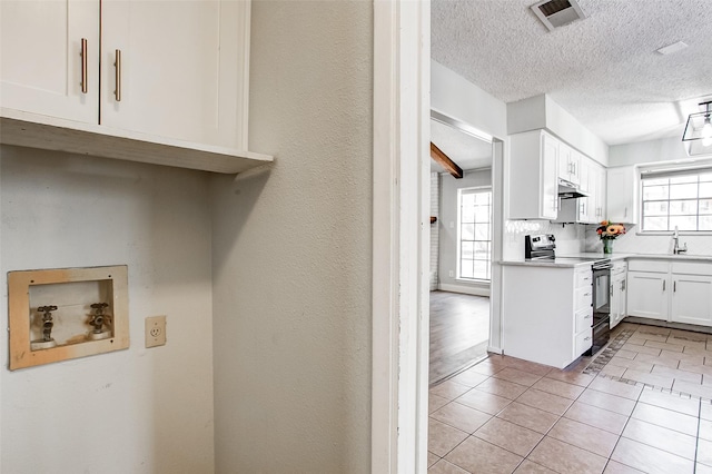 kitchen featuring plenty of natural light, black electric range oven, white cabinetry, and sink