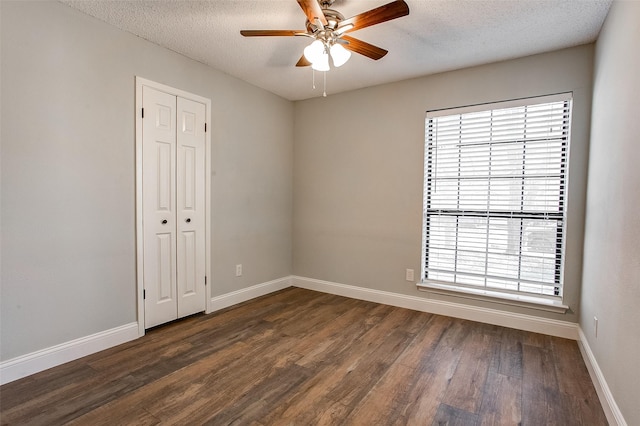 spare room with a textured ceiling, ceiling fan, and dark wood-type flooring