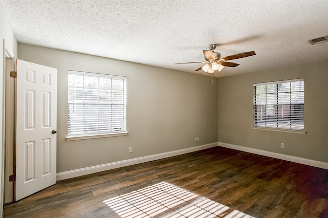 empty room featuring dark hardwood / wood-style flooring, a textured ceiling, and a wealth of natural light