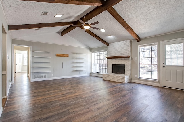 unfurnished living room featuring plenty of natural light, dark wood-type flooring, a textured ceiling, and a brick fireplace