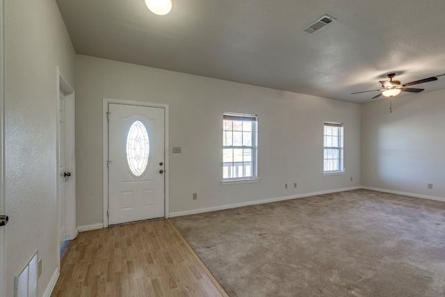 foyer with ceiling fan, light hardwood / wood-style floors, and a textured ceiling