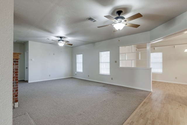 unfurnished room with a textured ceiling, light wood-type flooring, and plenty of natural light