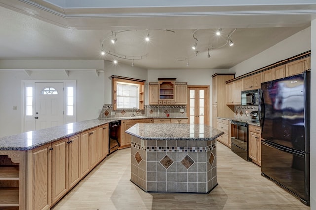 kitchen featuring backsplash, sink, black appliances, a center island, and light hardwood / wood-style floors