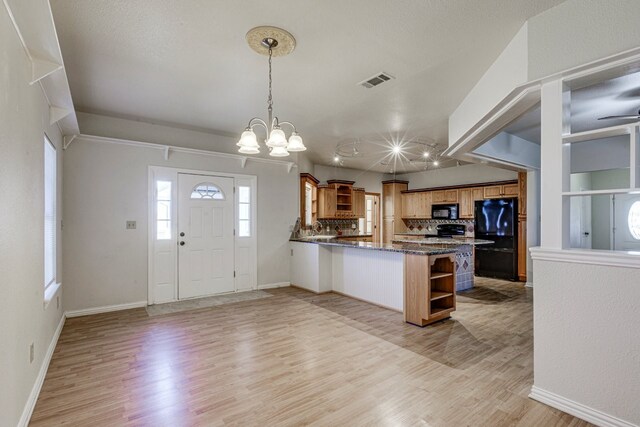 kitchen with kitchen peninsula, decorative backsplash, black appliances, light hardwood / wood-style flooring, and hanging light fixtures