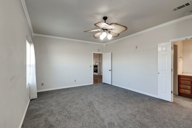 unfurnished room with a wealth of natural light, dark carpet, ceiling fan, and crown molding