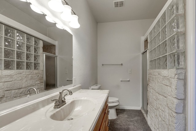 bathroom with toilet, an enclosed shower, and vanity