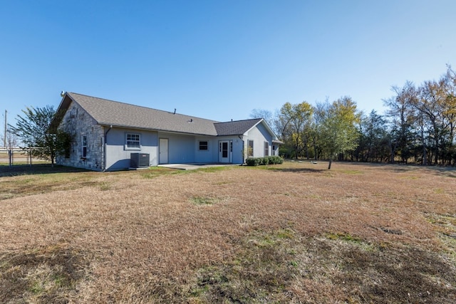 rear view of house with cooling unit and a lawn