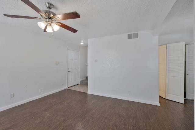 empty room featuring dark hardwood / wood-style flooring, a textured ceiling, and ceiling fan