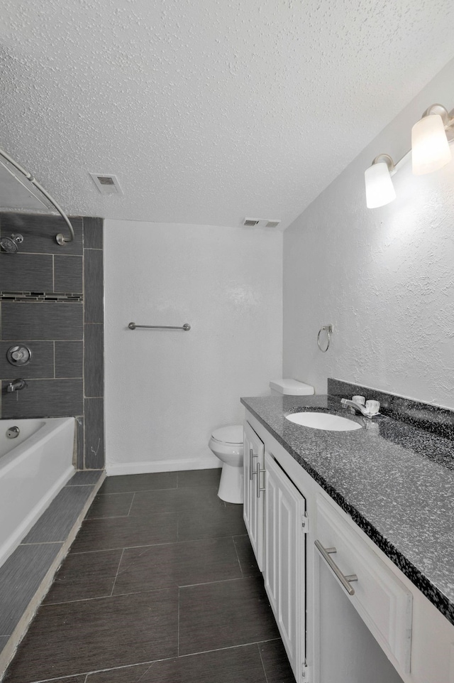 full bathroom featuring tiled shower / bath combo, vanity, a textured ceiling, and toilet