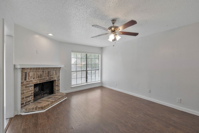 unfurnished living room featuring ceiling fan, a fireplace, dark hardwood / wood-style floors, and a textured ceiling