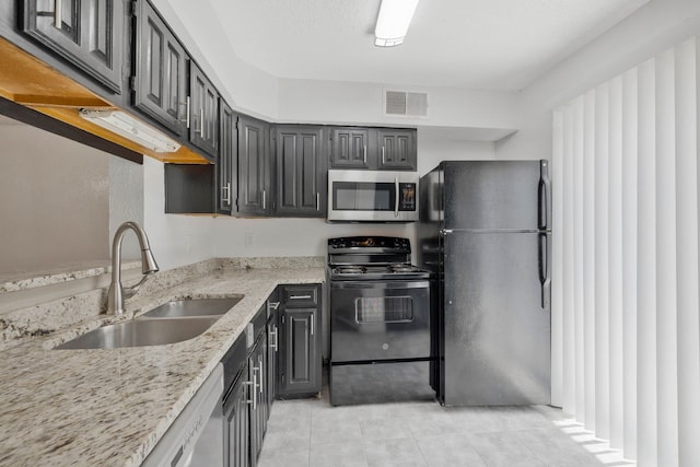 kitchen featuring light tile patterned flooring, light stone countertops, sink, and black appliances