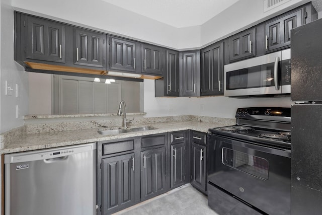 kitchen with light tile patterned flooring, sink, light stone counters, and black appliances