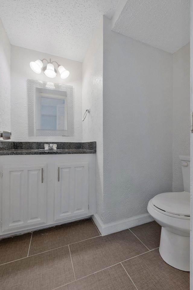 bathroom featuring tile patterned flooring, vanity, a textured ceiling, and toilet