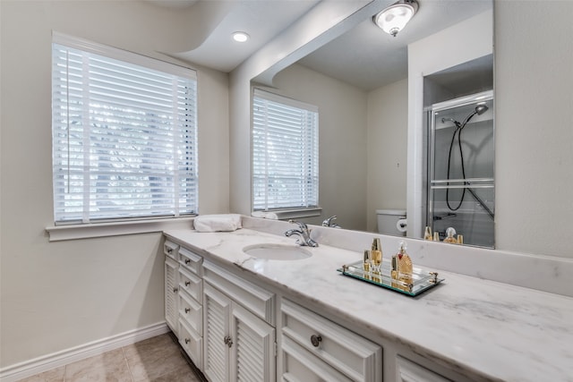 bathroom with tile patterned floors, vanity, a healthy amount of sunlight, and toilet