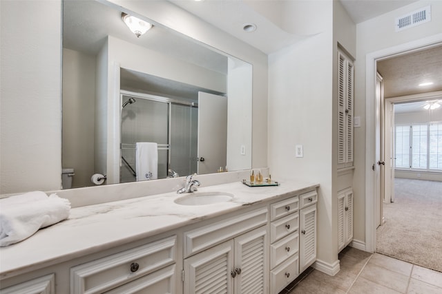 bathroom with tile patterned flooring, vanity, and a shower with door