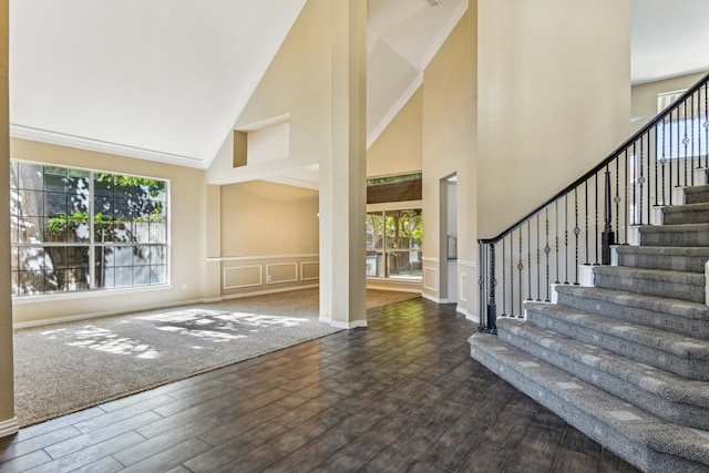 foyer with high vaulted ceiling, dark wood-type flooring, and ornamental molding