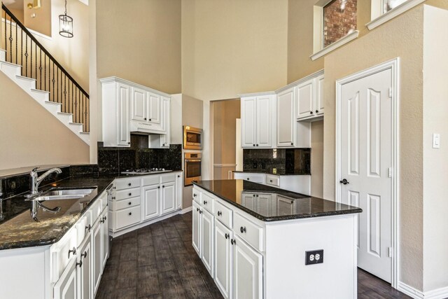 kitchen featuring a high ceiling, sink, dark hardwood / wood-style floors, appliances with stainless steel finishes, and white cabinetry