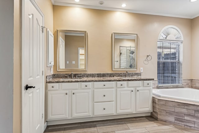 bathroom with tiled tub, crown molding, vanity, and wood-type flooring