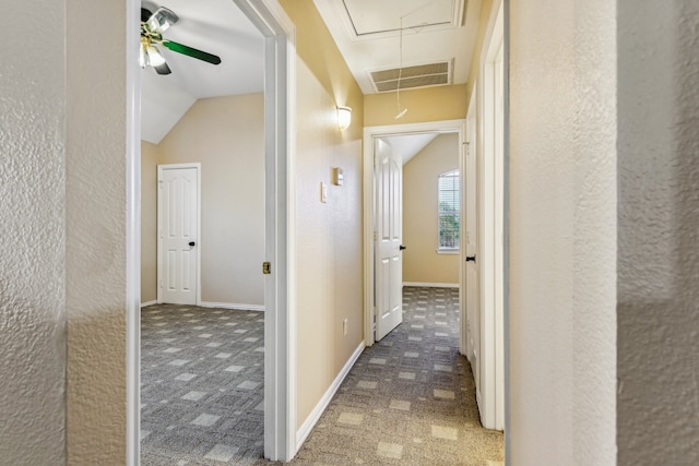 hall featuring dark colored carpet and lofted ceiling