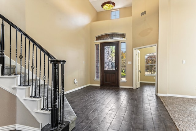 foyer entrance featuring a towering ceiling and dark wood-type flooring