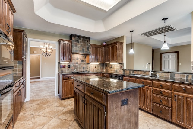 kitchen with decorative backsplash, dark stone counters, sink, decorative light fixtures, and a center island