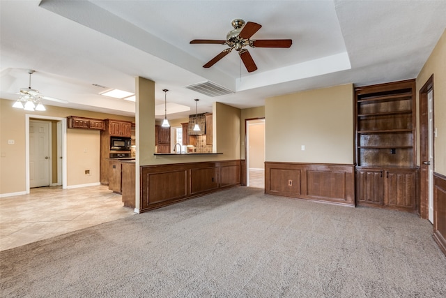 unfurnished living room featuring a tray ceiling, ceiling fan, and light colored carpet