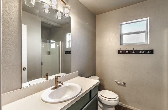 bathroom featuring vanity, a shower with shower door, and toilet