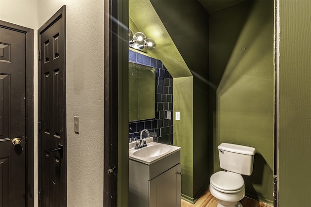 bathroom featuring hardwood / wood-style floors, decorative backsplash, toilet, and vanity