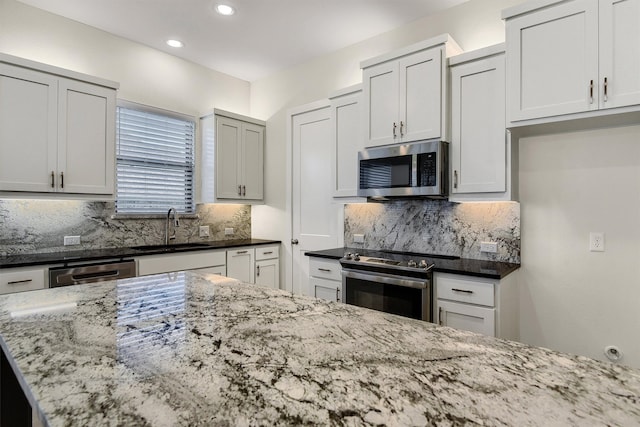 kitchen featuring backsplash, dark stone countertops, sink, and appliances with stainless steel finishes