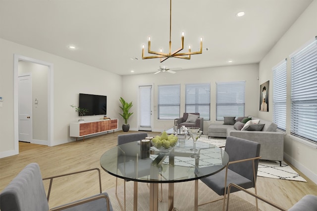 living room with ceiling fan with notable chandelier and light wood-type flooring