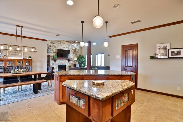 kitchen with light stone countertops, crown molding, a kitchen island, and pendant lighting