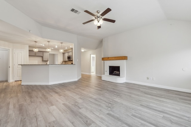 unfurnished living room featuring a fireplace, ceiling fan, light hardwood / wood-style flooring, and vaulted ceiling