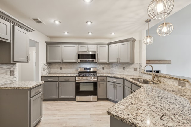 kitchen featuring gray cabinetry, sink, hanging light fixtures, stainless steel appliances, and kitchen peninsula