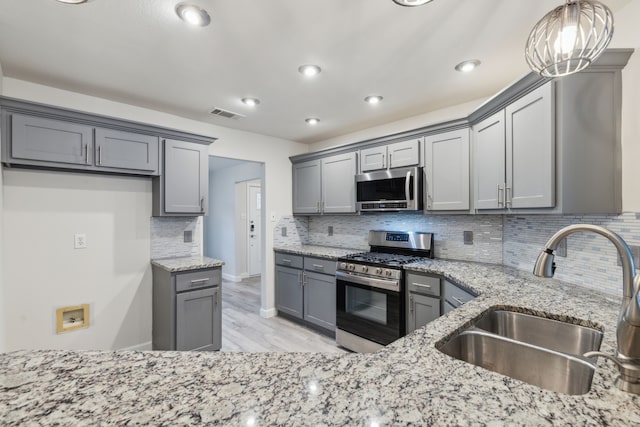 kitchen with gray cabinets, sink, stainless steel appliances, and decorative light fixtures