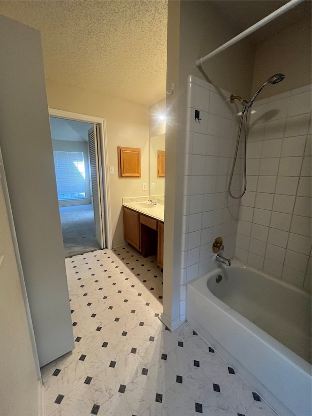 bathroom with vanity, a textured ceiling, and tiled shower / bath combo