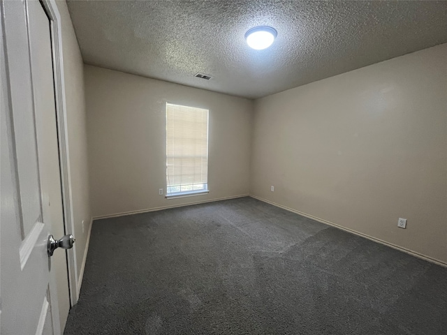 empty room featuring dark carpet and a textured ceiling