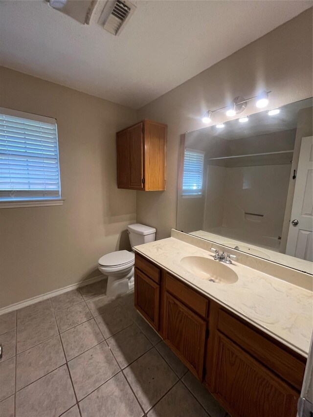 bathroom with tile patterned floors, vanity, toilet, and a shower