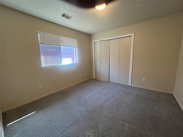 unfurnished bedroom featuring a closet, dark carpet, and a textured ceiling