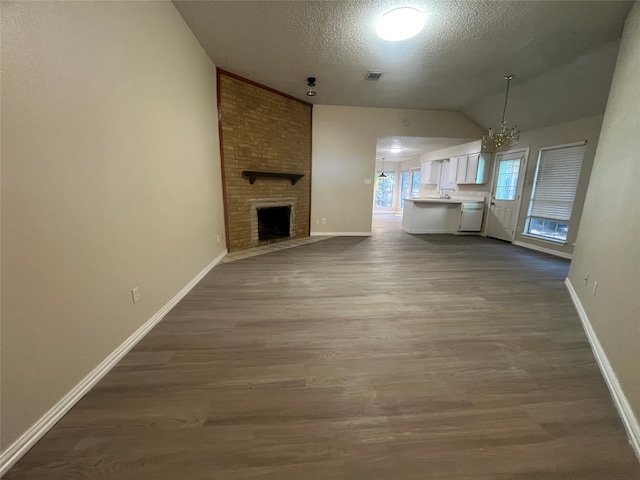 unfurnished living room featuring lofted ceiling, a fireplace, wood-type flooring, and a textured ceiling