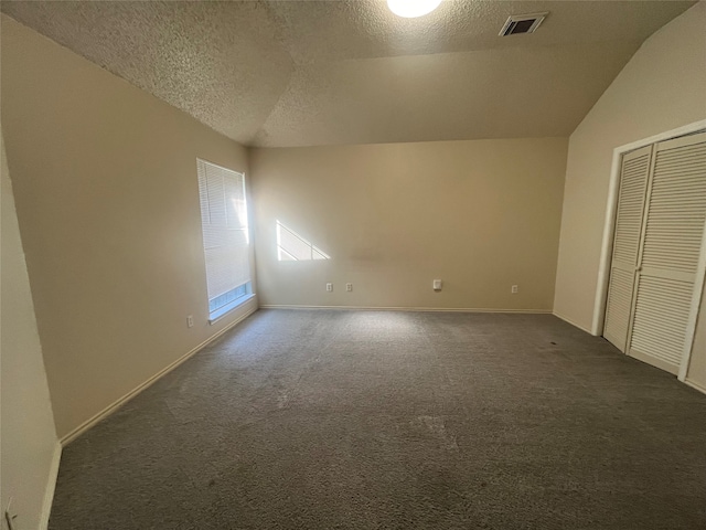 unfurnished bedroom featuring dark colored carpet, a textured ceiling, and vaulted ceiling