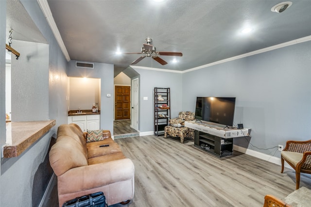 living room featuring light hardwood / wood-style flooring, ceiling fan, crown molding, and sink