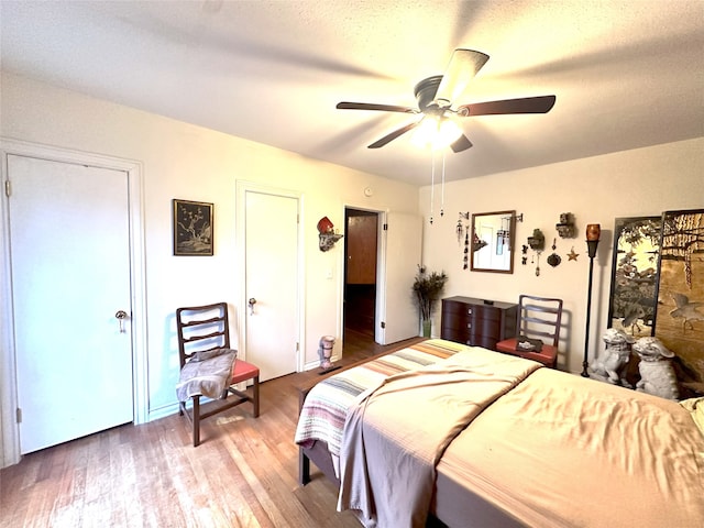 bedroom with hardwood / wood-style flooring, a textured ceiling, and ceiling fan