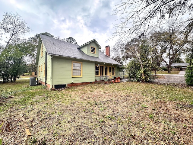 view of side of home with central AC and a lawn