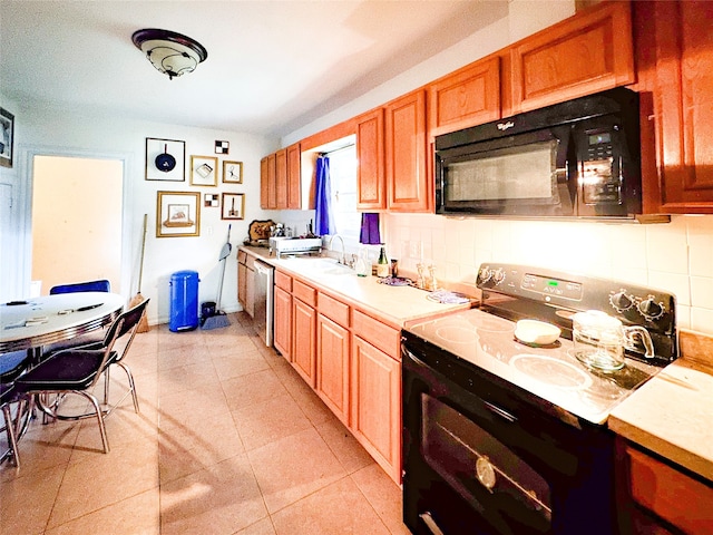 kitchen with light tile patterned floors, decorative backsplash, black appliances, and sink