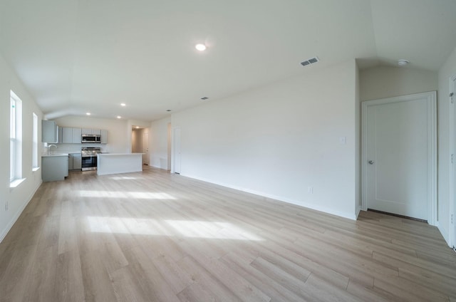 unfurnished living room featuring lofted ceiling, sink, and light wood-type flooring