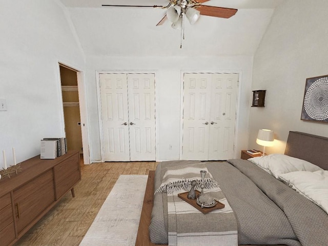 bedroom with ceiling fan, multiple closets, light wood-type flooring, and lofted ceiling