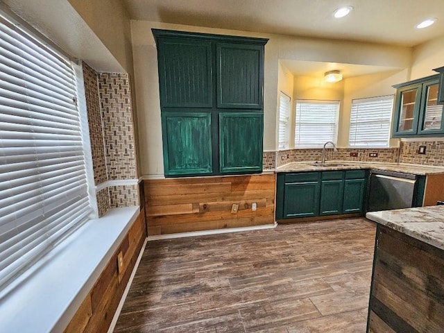 kitchen with light stone countertops, tasteful backsplash, stainless steel dishwasher, sink, and hardwood / wood-style floors